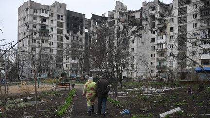 Deux personnes marchant dans des ruines à Marioupol (Ukraine), le 12 avril 2022. (ILYA PITALEV / SPUTNIK / AFP)