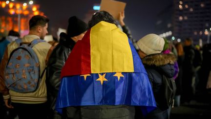 Un homme portant les drapeaux roumain et européen sur ses épaules participe à une manifestation contre Calin Georgescu, à Bucarest, le 27 novembre 2024, en Roumanie. (VADIM GHIRDA / AP / SIPA)