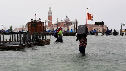 Une femme porte une valise à Venise, sous les eaux, le 29 octobre 2018. (MIGUEL MEDINA / AFP)