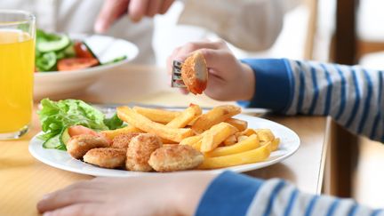 Un enfant mange des nuggets (photo d'illustration). (TOBIAS HASE / DPA / MAXPPP)