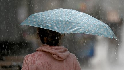 Une femme s'abrite de la pluie à Montpellier (Hérault), le 28 octobre 2021. (PASCAL GUYOT / AFP)