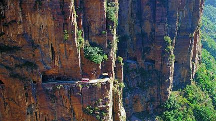 Des v&eacute;hicules empruntent la route &eacute;troite cr&eacute;&eacute;e &agrave; flanc de falaise qui permet de relier le village de Guoliang (Chine) au reste du pays, le 29 mai 2012. (QUIRKY CHINA NEWS / REX / SIPA)