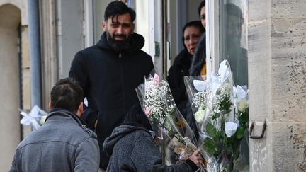 Des personnes déposent des fleurs devant la maison des parents de la fillette, le 26 avril 2023 à Rambervillers (Vosges). (JEAN-CHRISTOPHE VERHAEGEN / AFP)