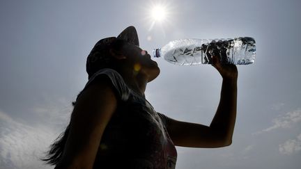 Une femme boit de l'eau à Quimper (Finistère), placé en vigilance orange canicule, le 20 juin 2017. (FRED TANNEAU / AFP)