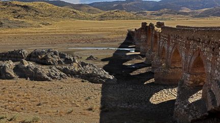 Sous le pont médiéval Puente de la Mesta à Villarta de los Montes,&nbsp;la rivière Guadiana s'est asséchée et a cèdé&nbsp;sa place à de la terre sèche et craquelée,&nbsp;le 16 août 2022. Le manque d'eau transforme la campagne espagnol en véritable paysage désertique. (THOMAS COEX / AFP)