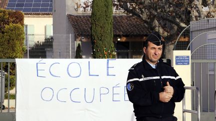 Un gendarme devant l'&eacute;cole Notre-Dame-de-Caderot&nbsp;&agrave; Berre-l'Etang (Bouches-du-Rh&ocirc;ne), le 7 d&eacute;cembre 2011. (ANNE-CHRISTINE POUJOULAT / AFP)