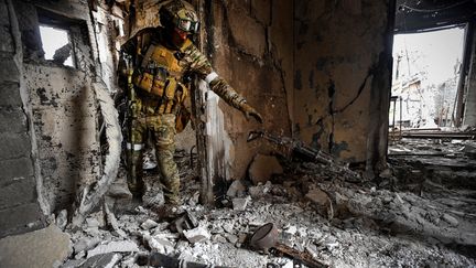 Un soldat russe récupère des armes trouvées lors d'une patrouille au théâtre dramatique de Marioupol, bombardé le 16 mars dernier, le 12 avril 2022. (ALEXANDER NEMENOV / AFP)