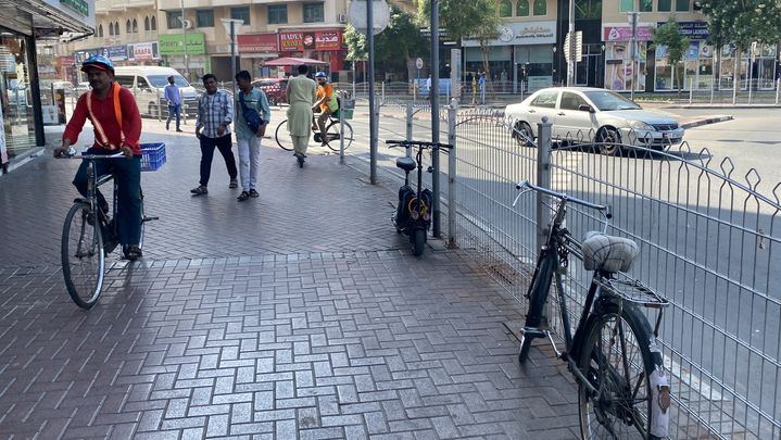 Des cyclistes et des vélos stationnés dans un quartier de Dubaï, loin des tours clinquantes des centres d'affaires, le 28 novembre 2023. (MARIE-ADELAIDE SCIGACZ / FRANCEINFO.FR)