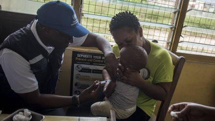 Un médecin de l'Organisation mondiale de la Santé (OMS) administre un vaccin antipaludique à un enfant dans une clinique au Ghana en avril 2019. (CRISTINA ALDEHUELA / AFP)