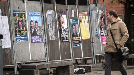 Un homme passe devant des panneaux électoraux avant les élections régionales, le 1er décembre&nbsp;2015, à Lille (Nord). (PHILIPPE HUGUEN / AFP)