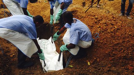 Des travailleurs humanitaires enterrent le corps d'une victime du virus Ebola, en Sierra Leone, le 18 juillet 2014. (HANDOUT / REUTERS)