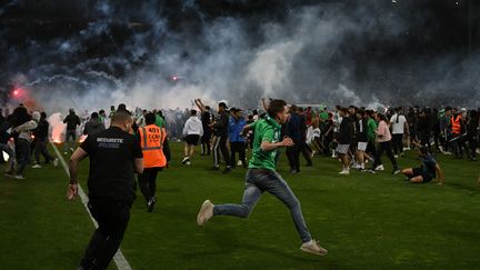 Des supporters de l'AS Saint-Etienne envahissent le terrain après la défaite face à Auxerre, dans le match de barrage pour éviter la descente en Ligue 2, le 29 mai 2022. (JEAN-PHILIPPE KSIAZEK / AFP)