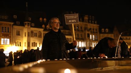 Un homme se recueille place de la Réunion, à Mulhouse (Haut-Rhin), en brandissant une pancarte "Nous sommes tous solidaires avec les juifs", mardi 19 février 2019. (MAXPPP)