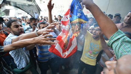 Des manifestants &eacute;gyptiens br&ucirc;lant un drapeau am&eacute;ricain devant l'ambassade des Etats-Unis, le 12 septembre 2012 au Caire (Egypte). (KHALED DESOUKI / AFP)