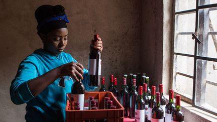 Assoumpata Uwamariya remplit une caisse à bouteilles avec son vin de betterave, le Karisimbi. (Jean BIZIMANA / REUTERS)