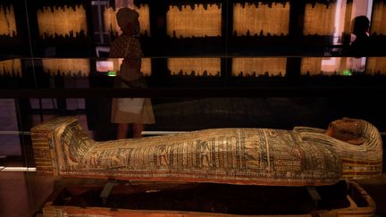 Des visiteurs observent un sarcophage abritant une momie au musée Granet d'Aix-en-Provence, le 18 septembre 2020 à la veille de l'ouverture officielle de l'exposition "Pharaon, Osiris et la momie" (CHRISTOPHE SIMON / AFP)