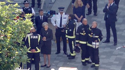 La Première ministre britannique Theresa May rencontre des secouristes, le 15 juin 2017, au pied de la Grenfell Tower, à Londres, dévastée par un incendie. (PETER NICHOLLS / REUTERS)