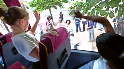 Au moment du départ en colonie de vacances, les enfants font signe à leurs parents. (FRED DUFOUR / AFP)