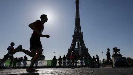 Des coureurs devant la Tour Eiffel lors de la 45e édition du Marathon de Paris, le 3 avril 2022. (SAMEER AL-DOUMY / AFP)