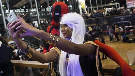 Une jeune femme costumée en Storm (X-men) prend un selfie en compagnie d'un avatar de Deadpool à la Paris Comic Con le 23 octobre 2015
 (ETIENNE LAURENT/EPA/MaxPPP)