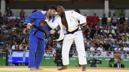 Teddy Riner (en blanc) face à l'Israélien Or Sasson (en bleu) en demi-finale des Jeux olympiques de Rio, le 12 août 2016. (JULIEN CROSNIER / AFP)