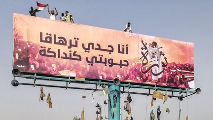 Immense affiche de rue montrant une image d'Alaa Salah, qualifiée de "kandaka" (souveraine antique) et devenue une icône des réseaux sociaux mondiaux. L'inscription en arabe signifiant : "Mon grand-père est Taharka (pharaon koushite au VIe avant notre ère, NDLR),&nbsp;mon aimée est Kadaka". (- / AFP)