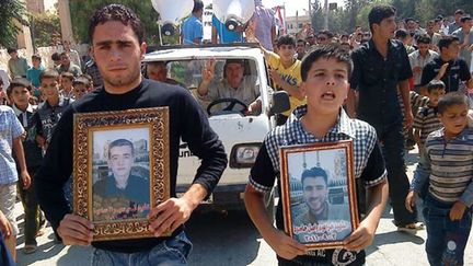 Des manifestants oppos&eacute;s au r&eacute;gime du pr&eacute;sident syrien Bachar Al-Assad d&eacute;filent avec les portraits de personnes mortes dans les violences, &agrave; Maaret Harma, dans la province d'Idlib (Syrie), le 9 septembre 2011. La photo a &eacute;t&eacute; prise par un journaliste, avec son t&eacute;l&eacute;phone portable. (AP / SIPA)