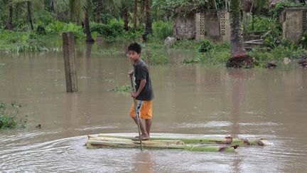 Un jeune gar&ccedil;on sur un radeau de fortune, le 4 d&eacute;cembre2012, &agrave; Pantukan, une ville de l'&icirc;le de Mindanao (Philippines). ( AFP )