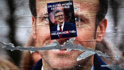 Un affiche de campagne d'Emmanuel Macron pour l'élection présidentielle 2022 recouverte d'un autocollant de Jean-Luc Mélenchon, à Paris, le 19 avril 2022. (JOEL SAGET / AFP)