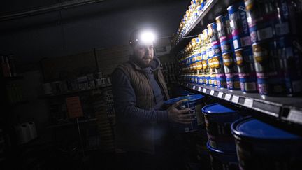 Un vendeur travaille dans le noir lors d'une panne de courant à Kiev, en Ukraine, le 21 novembre 2022. (METIN AKTAS / ANADOLU AGENCY / AFP)