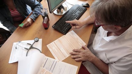 Un médecin remplit une feuille de soin lors d'une consultation. (VINCENT ISORE / MAXPPP)