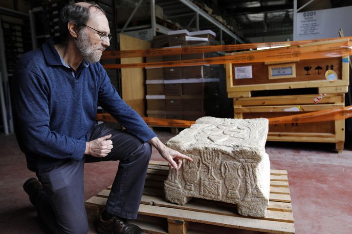 Le professeur Gideon Avni, directeur de la Division archéologique de l'Autorité des Antiquités israéliennes, montre le candélabre (Menorah) à sept branches inscrit sur la pierre de Magdala découverte dans une Synagogue de Galilée.
 (MENAHEM KAHANA / AFP)