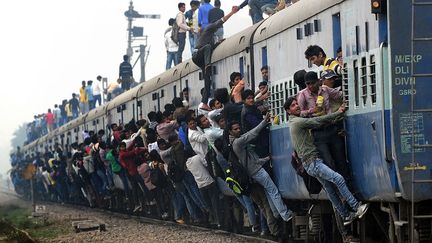 Des passagers s'accrochent aux wagons d'un train bond&eacute; dans la banlieue de New Delhi (Inde), le 25 f&eacute;vrier 2015. (MONEY SHARMA / AFP)