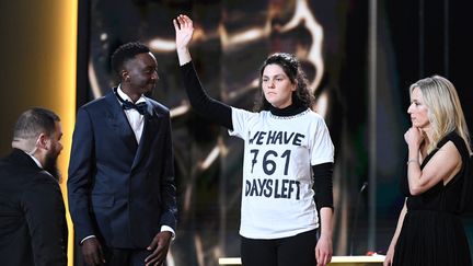 Une militante écologiste sur la scène de l'Olympia, à Paris, lors des César 2023, le 24 février 2023. (BERTRAND GUAY / AFP)