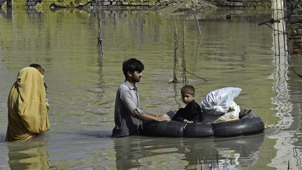 Une famille dans une zone inondée du district de Charsadda (Pakistan), le 29 août 2022. (ABDUL MAJEED / AFP)