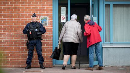 Un policier devant un bureau de vote d'Hénin-Beaumont (Pas-de-Calais), le 23 avril 2017, jour du premier tour de l'élection présidentielle. (KAY NIETFELD / AFP)