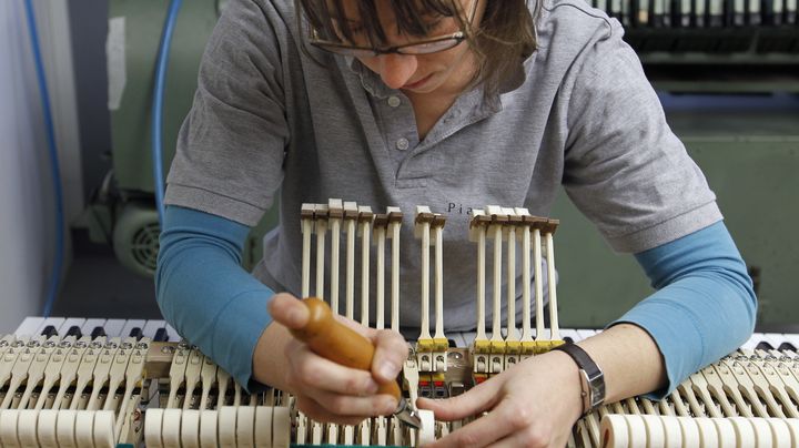 Une employ&eacute;e de la manufacture Pleyel travaille sur un piano &agrave; l'atelier de fabrication de Saint-Denis (Seine-Saint-Denis), le 3 d&eacute;cembre 2010. (FRANCOIS GUILLOT / AFP)