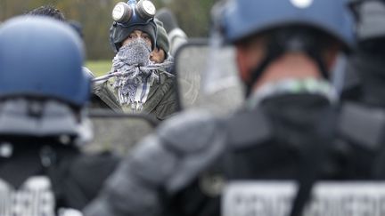 Un manifestant au visage dissimul&eacute;, fait face aux forces de l'ordre, d&eacute;ploy&eacute;es pour d&eacute;loger les opposants du projet d'a&eacute;roport &agrave; Notre-Dame-des-Landes, vendredi 23 novembre 2012.&nbsp; (STEPHANE MAHE / REUTERS )