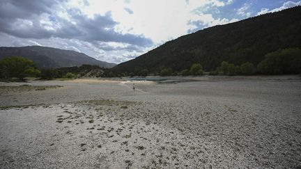 Un homme marche au bord du lac de Castillon, partiellement asséché, à Saint-André-les-Alpes (Alpes-de-Haute-Provence), le 28 juin 2022. (CHRISTOPHE SIMON / AFP)