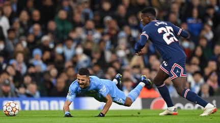 Le milieu de terrain de Manchester City, Riyad Mahrez, victime d'une faute du latéral parisien Nuno Mendes, lors de Manchester City-PSG le 24 novembre 2021. (PAUL ELLIS / AFP)