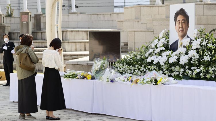 Japanese women pray in front of a flower stand near the funeral site of former Japanese Prime Minister Shinzo Abe, who was assassinated in the street in July 2022. (MAXPPP)