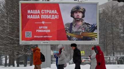 Des personnes passent devant un panneau avec l'inscription "Notre pays, notre victoire" à Saint-Petersbourg le 16 janvier 2024. (OLGA MALTSEVA / AFP)