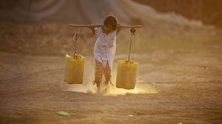 Un enfant transporte de l'eau dans une fabrique de briques pr&egrave;s de Rangoun (Birmanie), le 11 mars 2014. (YE AUNG THU / AFP)