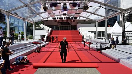 Le personnel du Festival déroule le tapis rouge lors du lancement de la 74e édition du Festival de Cannes, dans le sud de la France, le 6 juillet 2021. (JOHN MACDOUGALL / AFP)