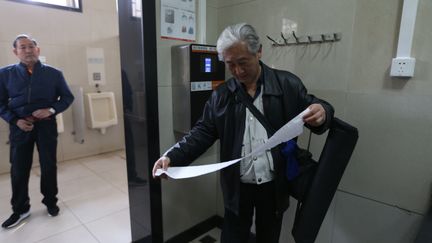 Un homme utilise le distributeur de papier toilette à reconnaissance faciale, au Temple du Ciel de Pékin (Chine), le 18 mars 2017. (BEI PIAO / IMAGINECHINA / AFP)