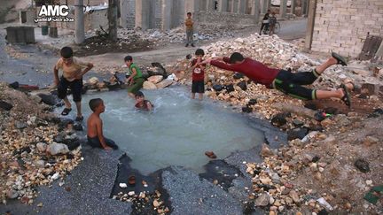 un trou d'obus fait office de piscine où s'amusent de jeunes Syriens plongés dans le plus grand dénuement. Capitale économique de Syrie avant la guerre, Alep est divisée, depuis 2012, en quartiers Ouest tenus par le régime et en secteurs Est sous contrôle des rebelles. Ces derniers sont bombardés au quotidien par les avions de l'armée syrienne et ceux de son allié russe. (ALEP MEDIA CENTER /Sipa - Octobre 2016)