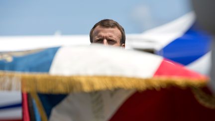 Emmanuel Macron caché par un drapeau français à l'aéroport de Cayenne, en Guyane, le 26 octobre 2017. (RONAN LIETAR / POOL)