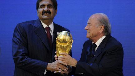 L'émir du Qatar, Hamad bin Khalifa Al Thani, reçoit le trophée Jules Rimet des mains de Sepp Blatter, président de la Fifa (PHILIPPE DESMAZES / AFP)