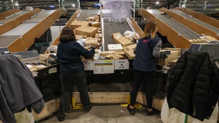 Employées d'une société privée triant des colis sur des tapis roulants, le 5 décembre 2023. (DENIS CHARLET / AFP)