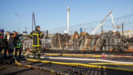 Les pompiers français se tiennent devant l'usine de Lubrizol endommagée à Rouen, Seine-Maritime, le 27 septembre 2019, à la suite d'un incendie. (LOU BENOIST / AFP)